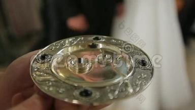 婚礼期间，在教堂里，人们用手握着金盘上的两枚结婚戒指